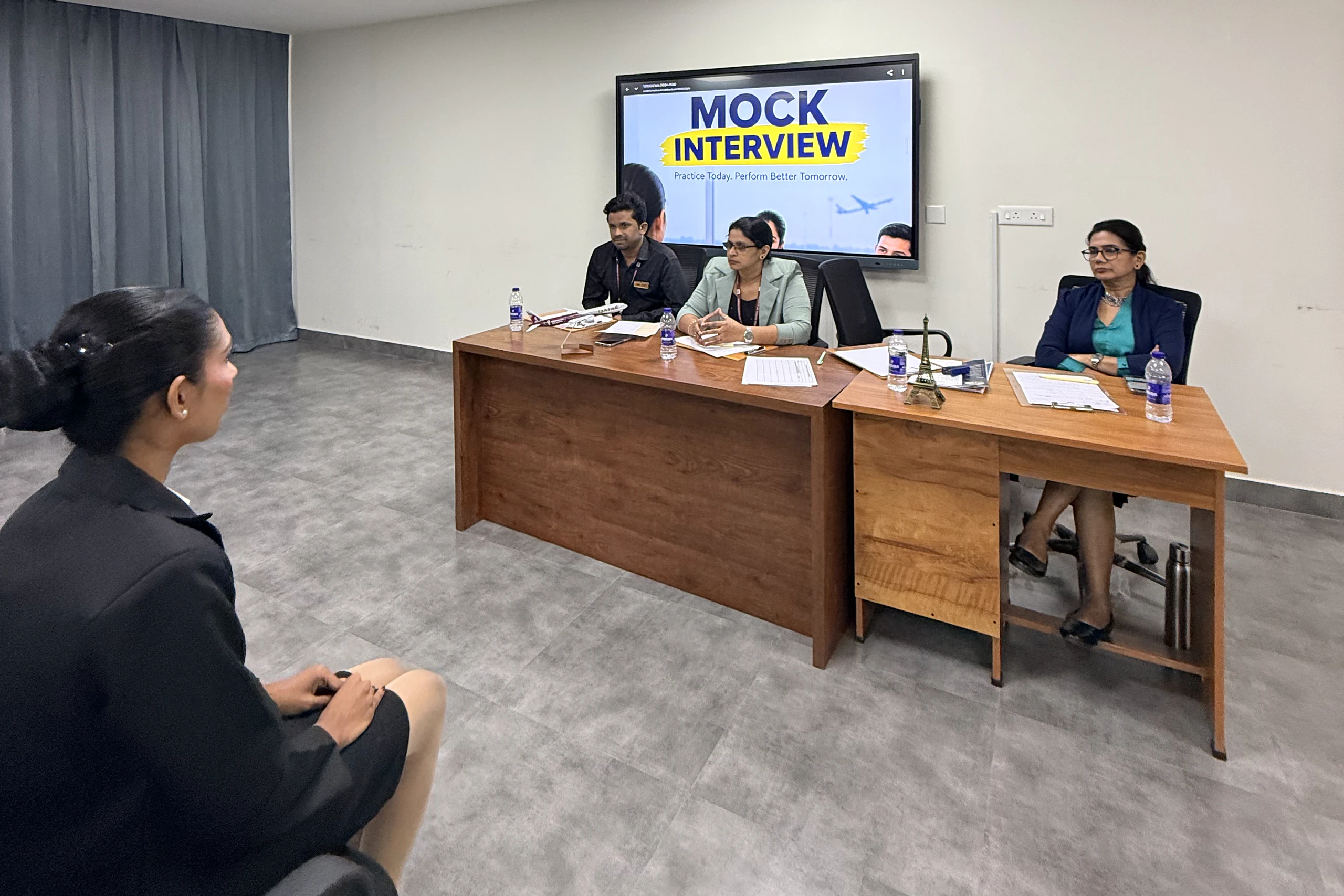 A student seated before a panel under a screen reading Mock Interview