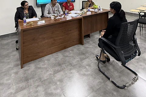 A student seated before an interview panel