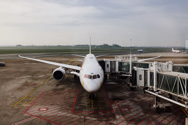 A passenger aircraft parked at an airport gate with a boarding bridge attached