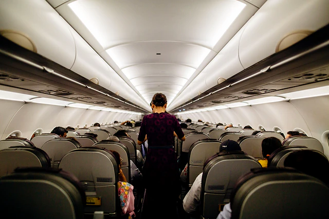 A cabin crew member walking along the aisle of a passenger aircraft